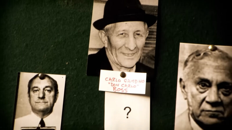 crime board featuring old black-and-white photographs of key figures in the Gambino crime family, with "Carlo Gambino" labeled as the boss