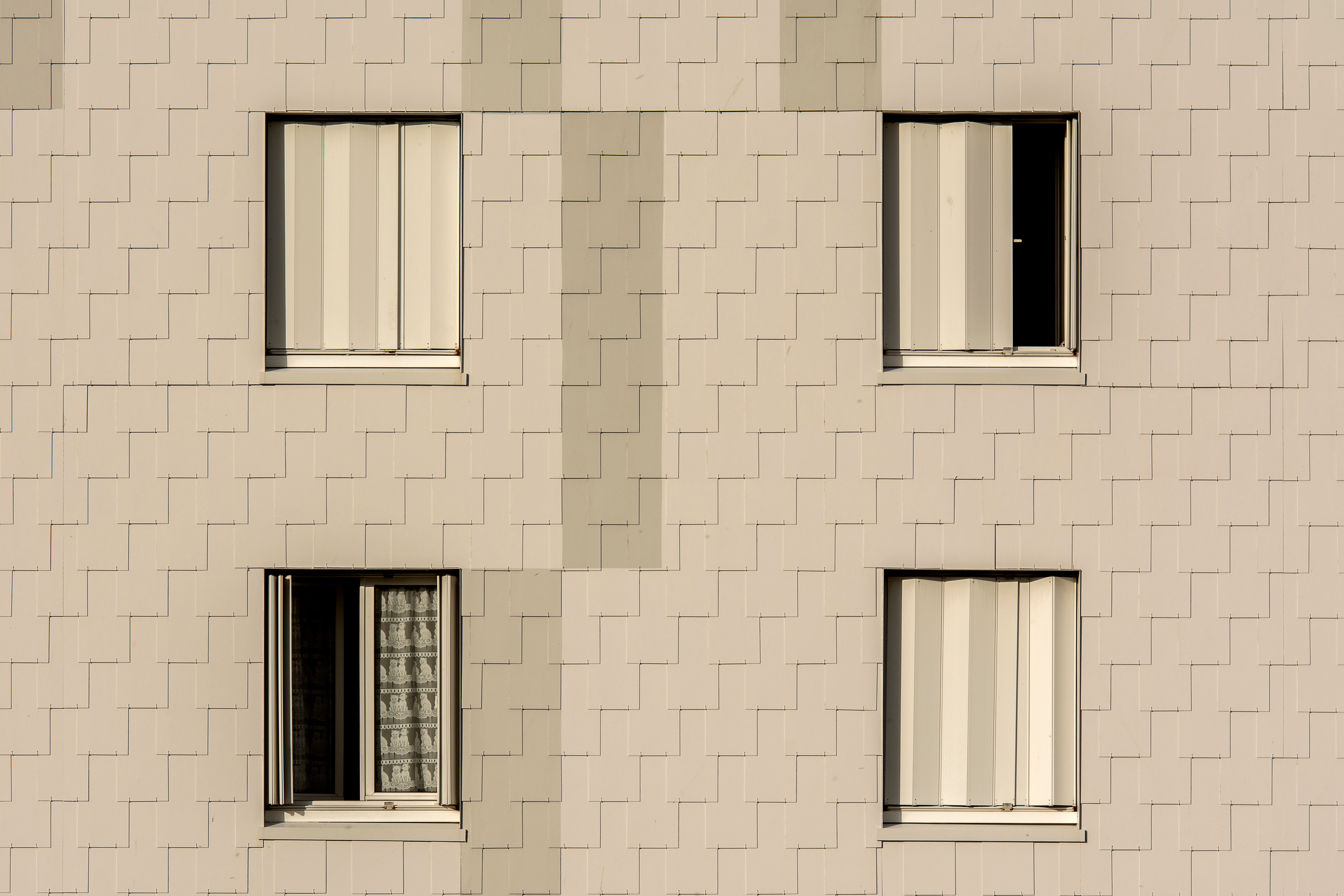 Close-up of a modern apartment building facade with symmetrical windows and beige cladding