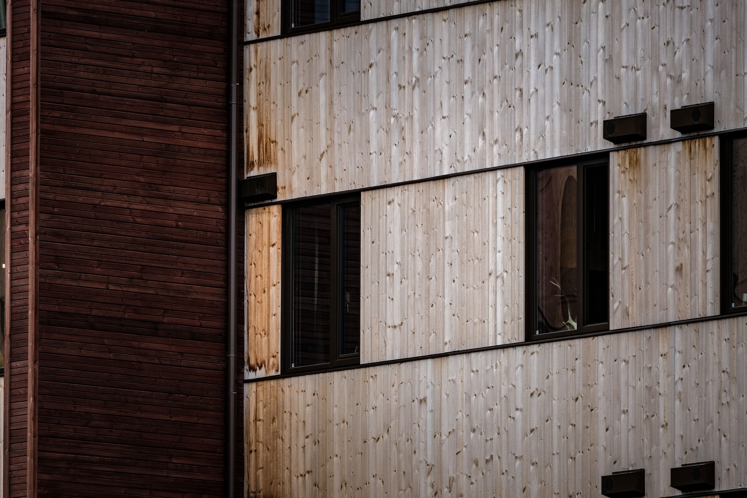 Close-up of a modern building facade with alternating wooden panels and windows